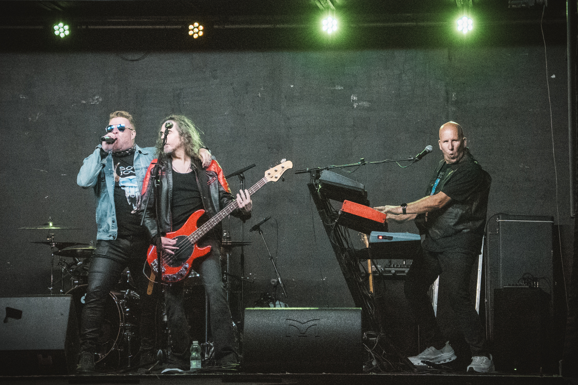 Singer, bassist and keyboard player under green stage lights